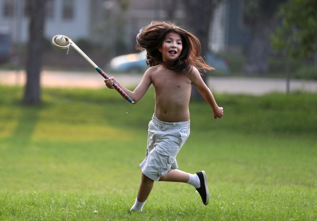 A young lacrosse player with a traditional wooden stick looks for an open teammate to pass to. (Courtesy David Joles)