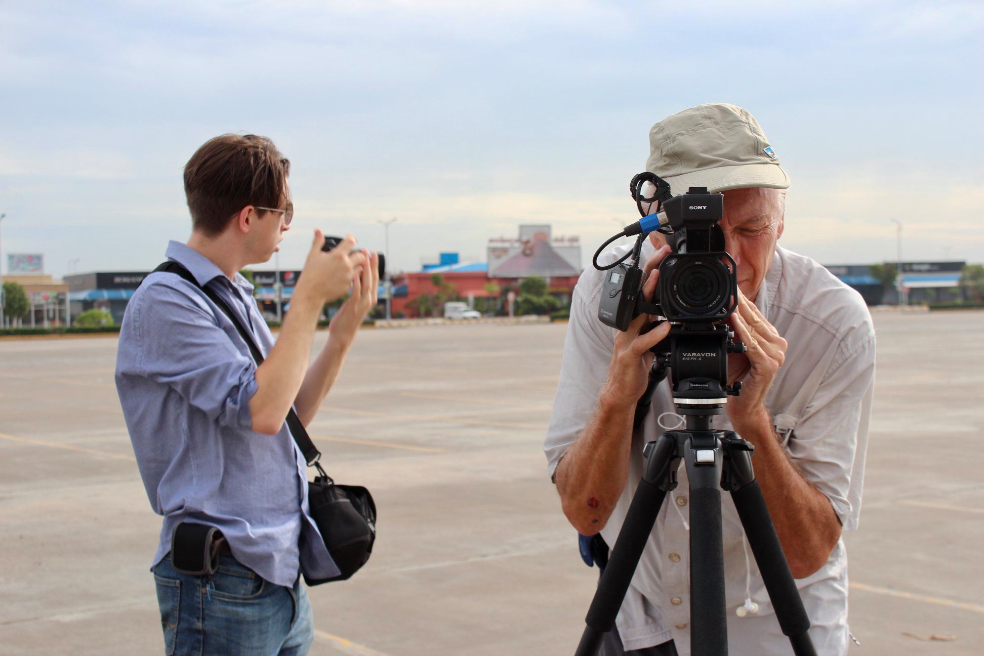 Lancaster and photographer Tom Adair shoot images of Phnom Penh's construction boom from an empty parking lot. Security asked them to leave shortly after.  (Credit: Sarah Clune Hartman)
