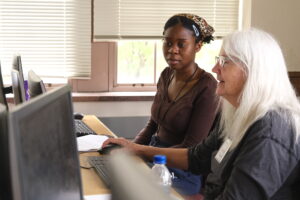 Student sitting with volunteer at computer.