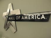 photo of the Mall of America logo on the Mall wall. It is a silver star with a banner shooting off it, that says, "MALL OF AMERICA"